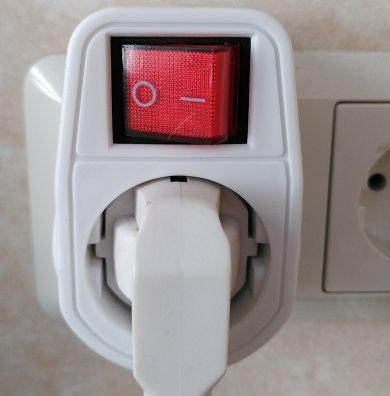 Energie Stecker in einem Mehrfachstecker und oben ein Licht, welches anzeigt, ob der Mehrfachstecker angeschaltet ist oder nicht